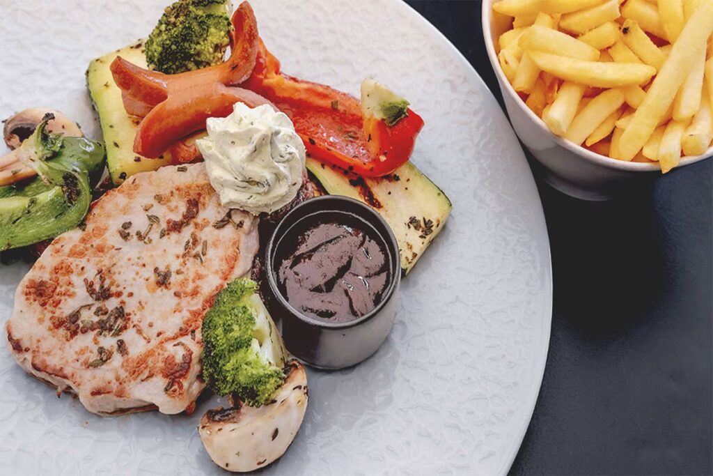 Professionelle Foodfotografie eines Grilltellers mit Gemüse und Pommes