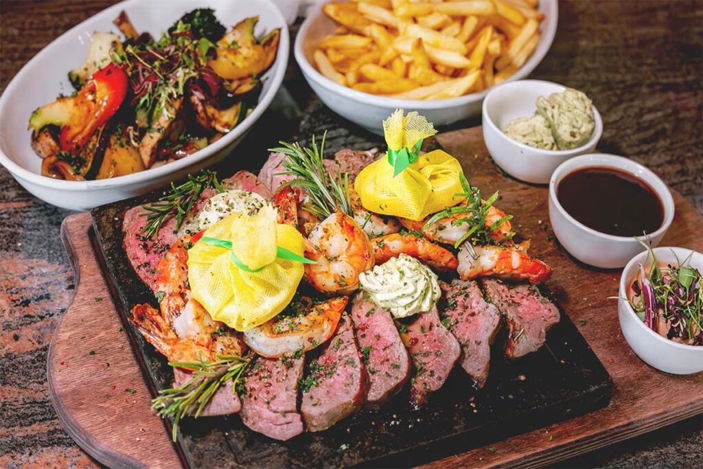 Foodfotografie von Steak und Garnelen auf heißem Stein mit Beilage