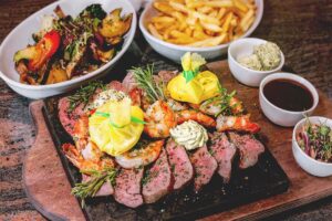 Foodfotografie von Steak und Garnelen auf heißem Stein mit Beilage